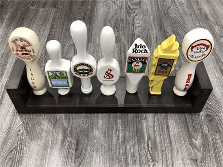 7 PORCELAIN BEER TAPS ON A DISPLAY STAND